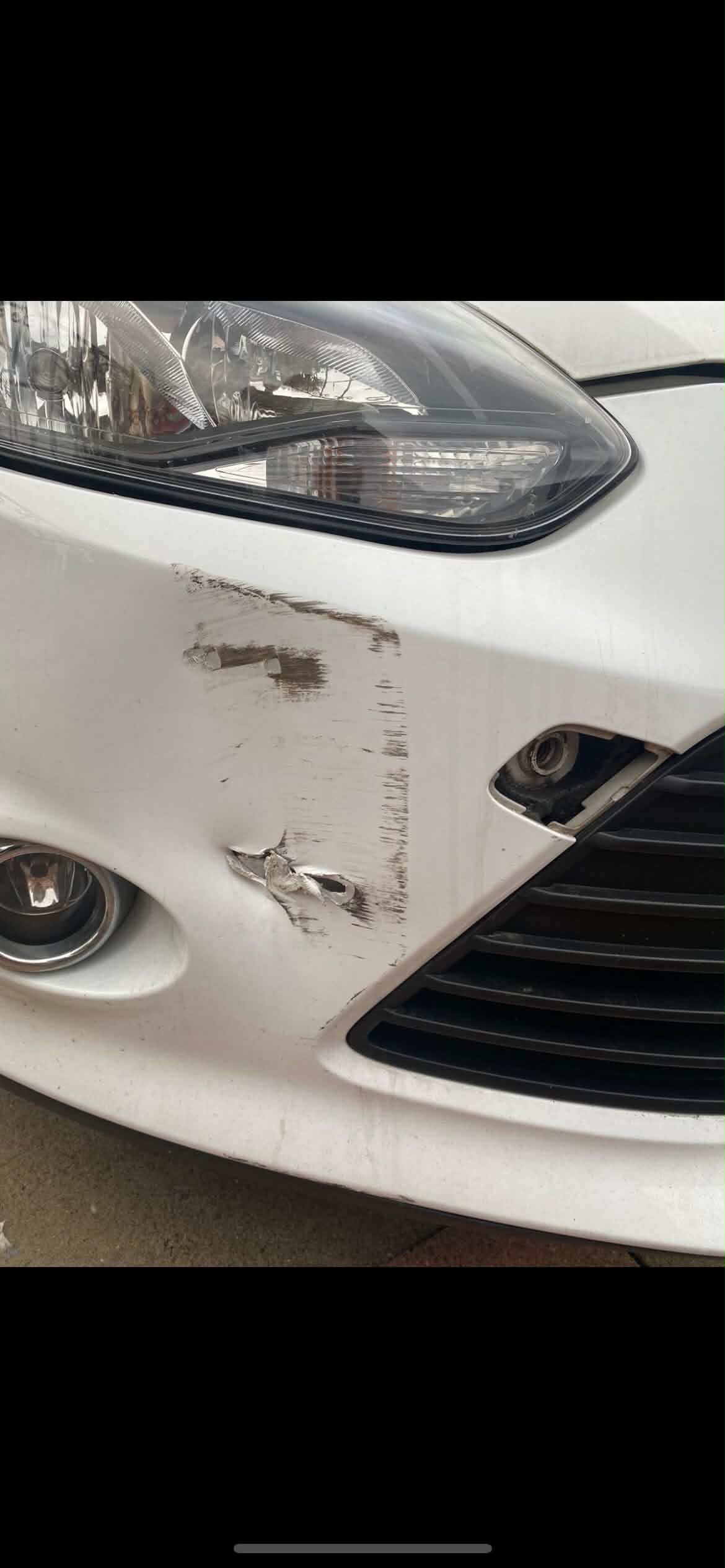 Car front bumper before bodywork repair, showing scuffing and scratches