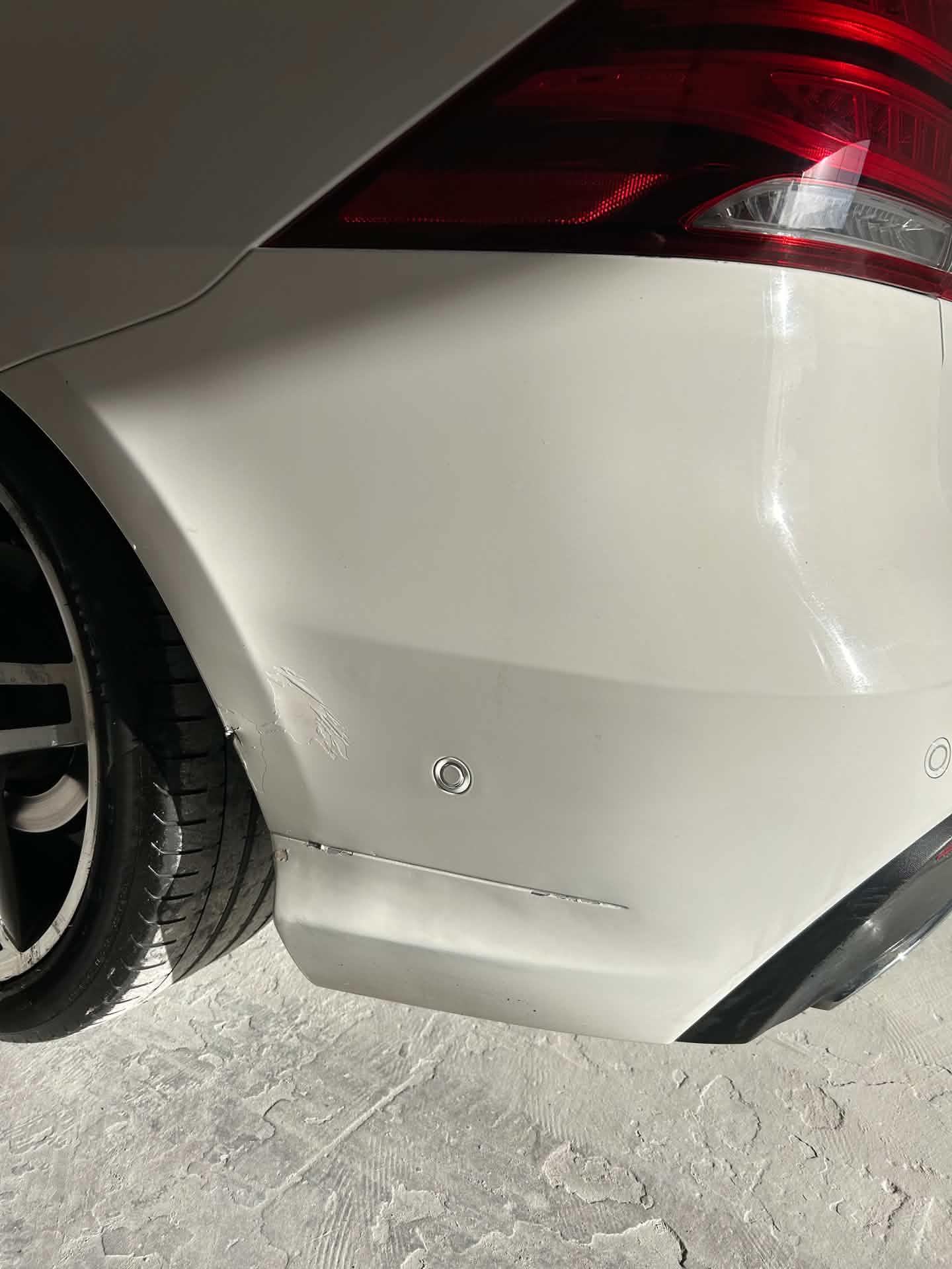 White car rear bumper before repair, scuff visible
