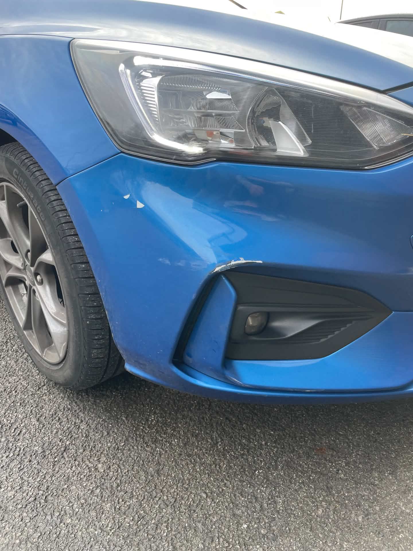 Blue car front bumper before repair, scuff visible