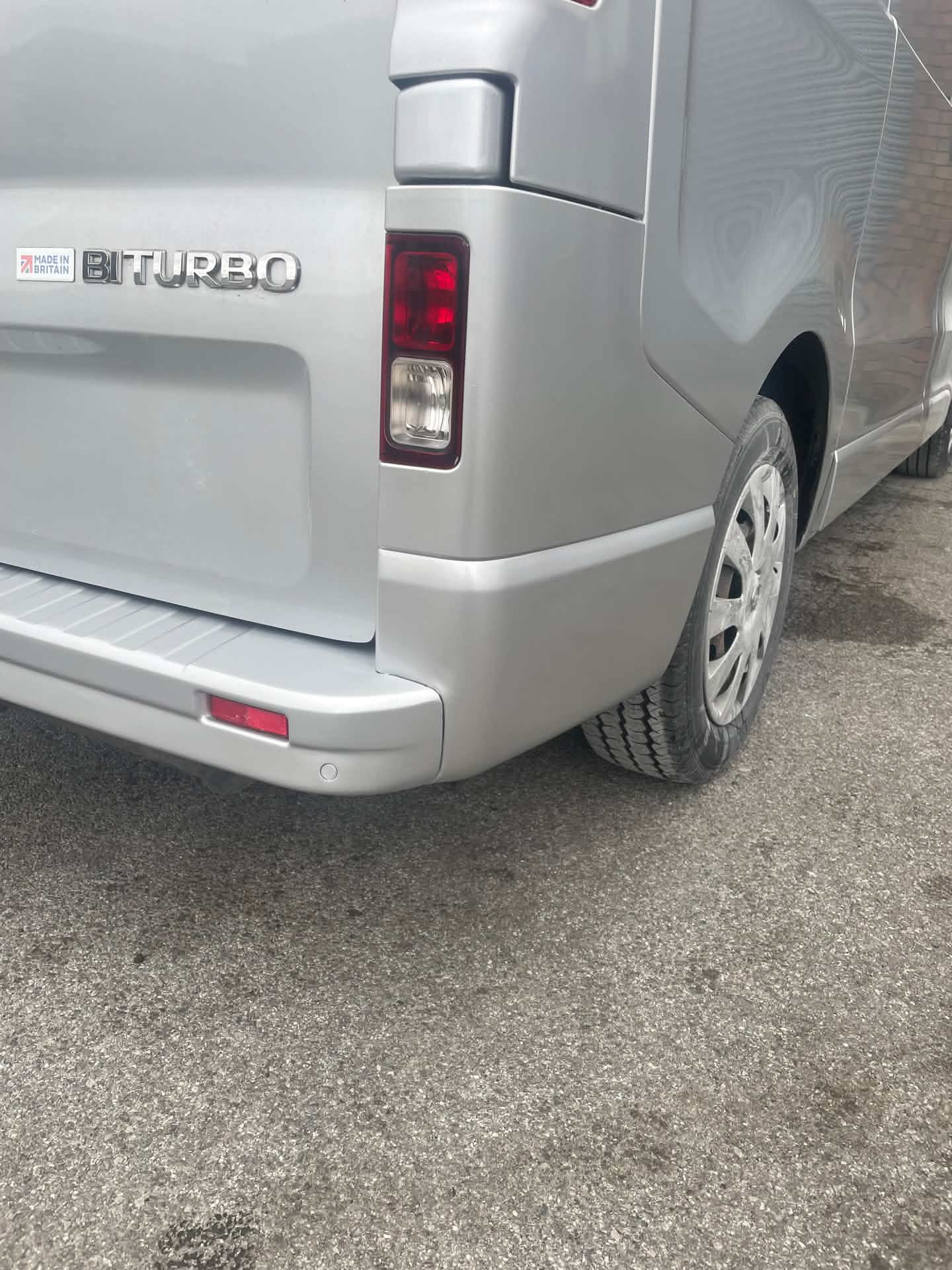 Silver van rear bumper before repair, crack visible near the corner