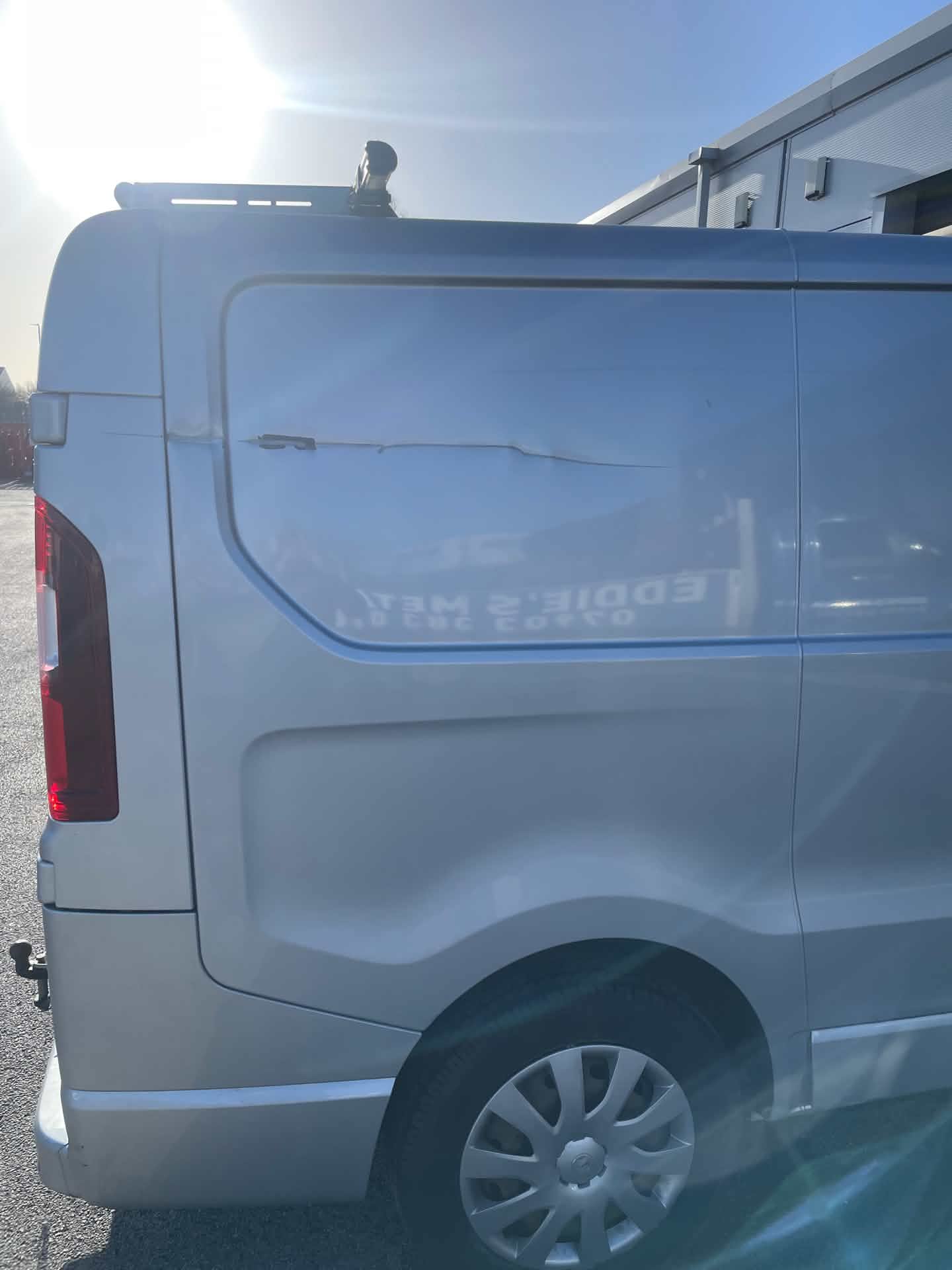 Van rear quarter panel before bodywork repair, showing a scratch through the paintwork